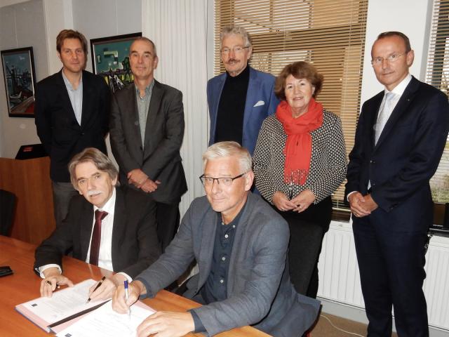 Burgemeester Gerard Beukema (links) en Jan Koolhof, voorzitter Stichting DelfSail 2021 tekenen de uitvoeringsovereenkomst. Staand v.l.n.r.: Arjen Luinenburg, gemeente Delfzijl, de wethouders Hans Ronde en Jan Menninga, Jeannette Blijdorp (directeur DelfSail 2021) en Johan Smit (penningmeester DelfSail 2021).